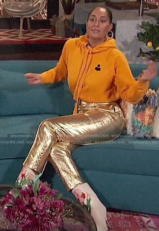 Tracee Ellis Ross's yellow hoodie, gold pants, and floral boots on Busy Tonight