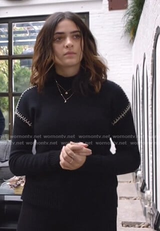 Olive's black sweater with white stitching on Manifest