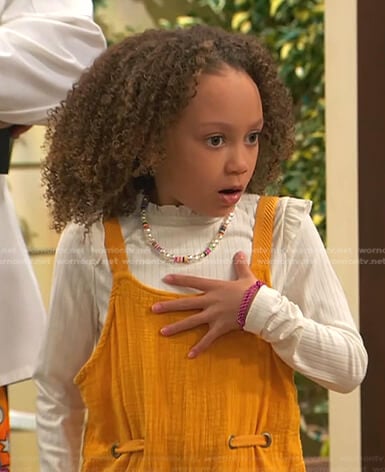 Alice's white ribbed ruffle top and orange overalls on Ravens Home