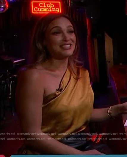 Emily Orozco's gold satin one shoulder top on Access Hollywood