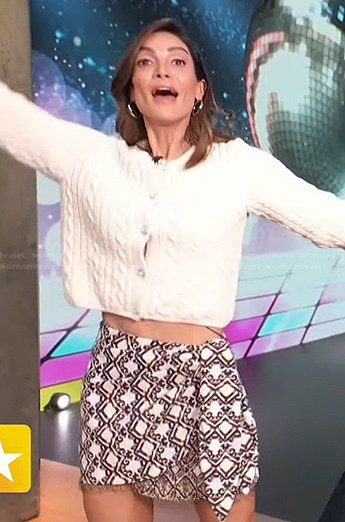 Courtney Lopez's white cardigan and printed mini skirt on Access Hollywood