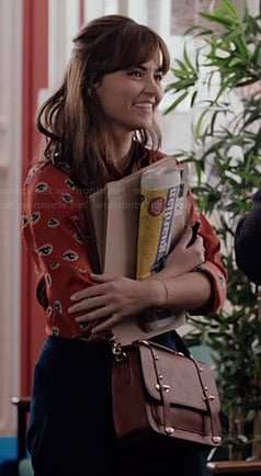 Clara’s orange eye print shirt and tan bag on Doctor Who