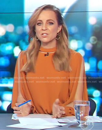 Carrie’s orange long slit sleeve top on The Project