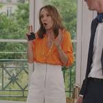 Sylvie’s orange blouse and white high waist pants on Emily in Paris