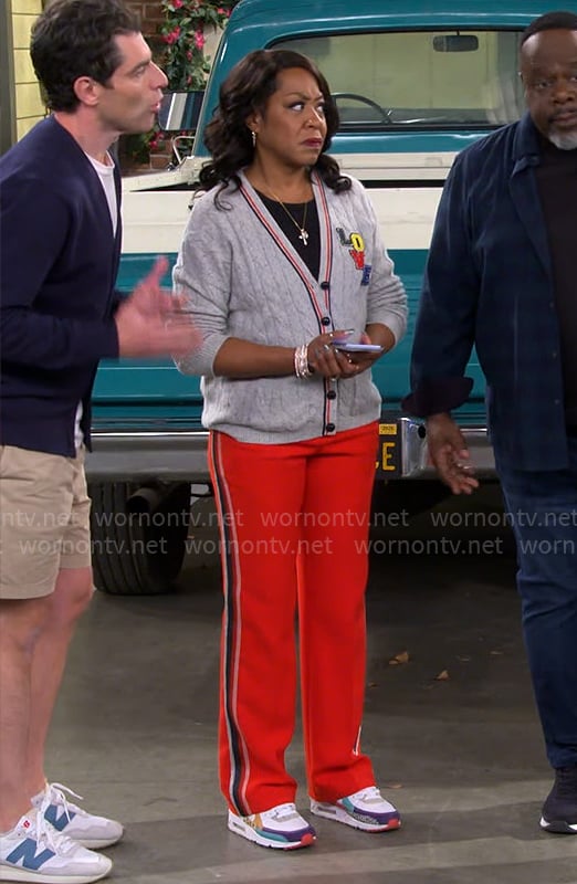 Tina’s grey LOVE cardigan and red stripe pants on The Neighborhood