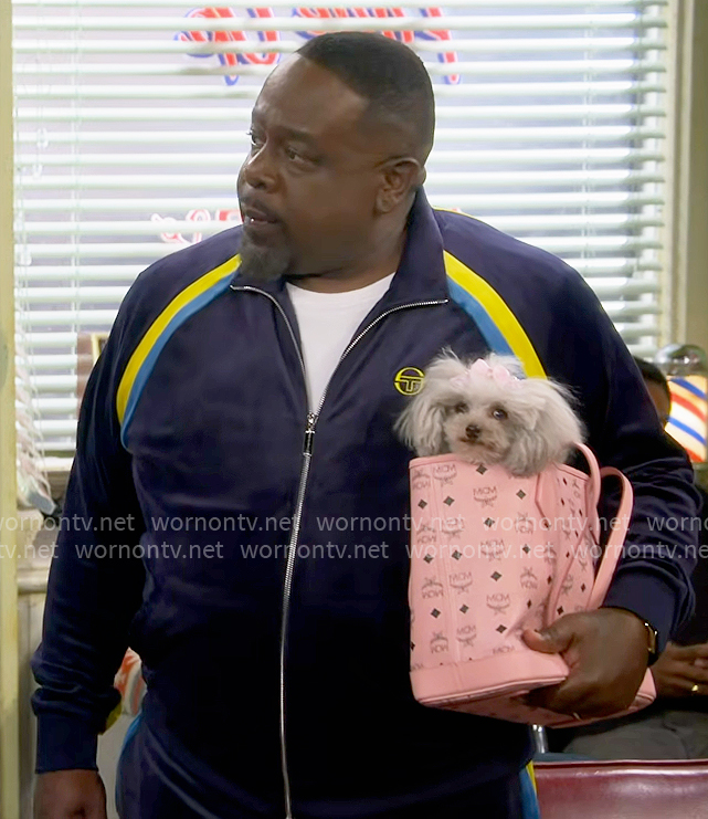 Calvin’s navy velour tracksuit and pink dog bag on The Neighborhood